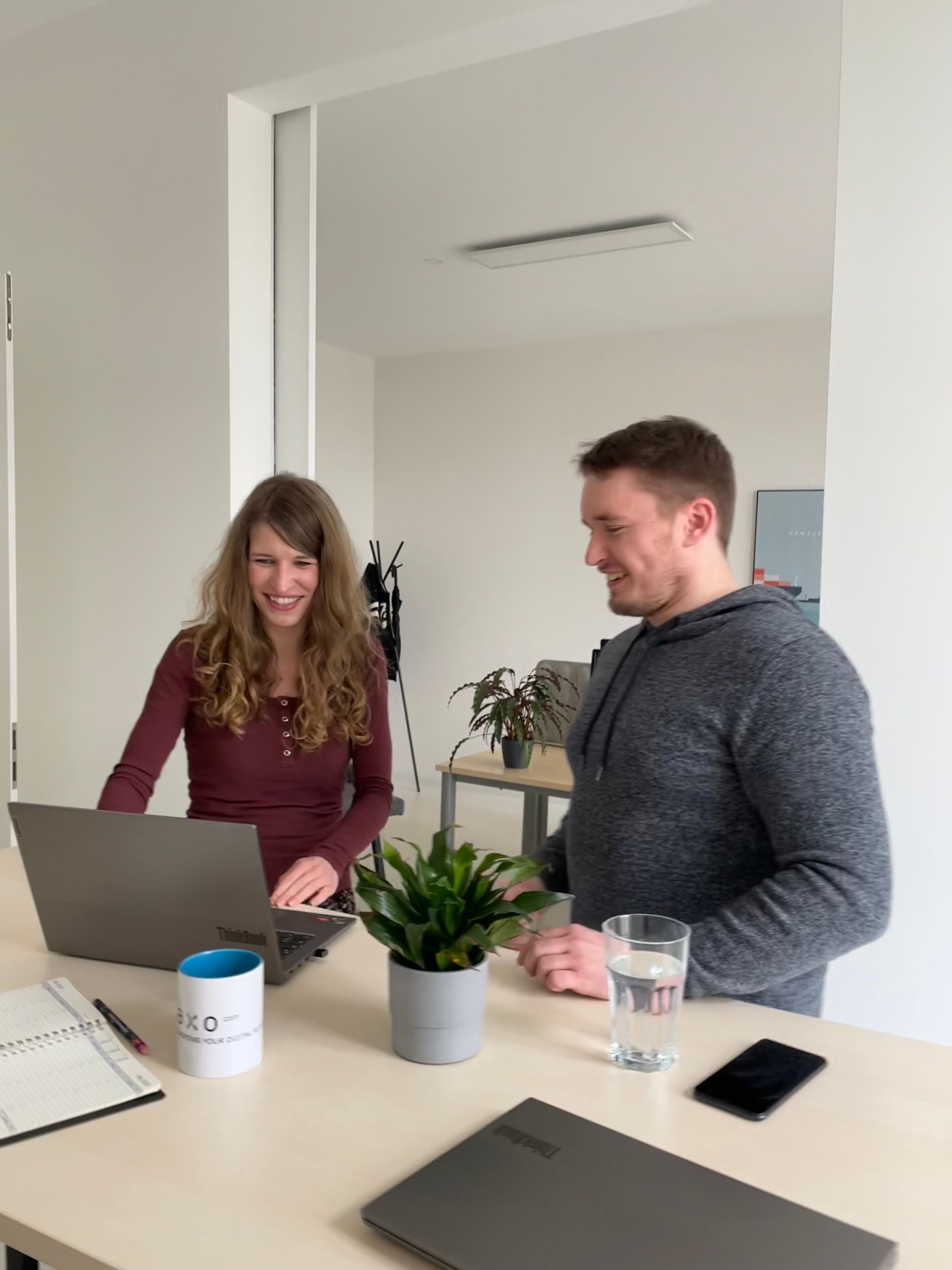 2 Kolleg:innen müssen während einer internen Unterhaltung lachen.