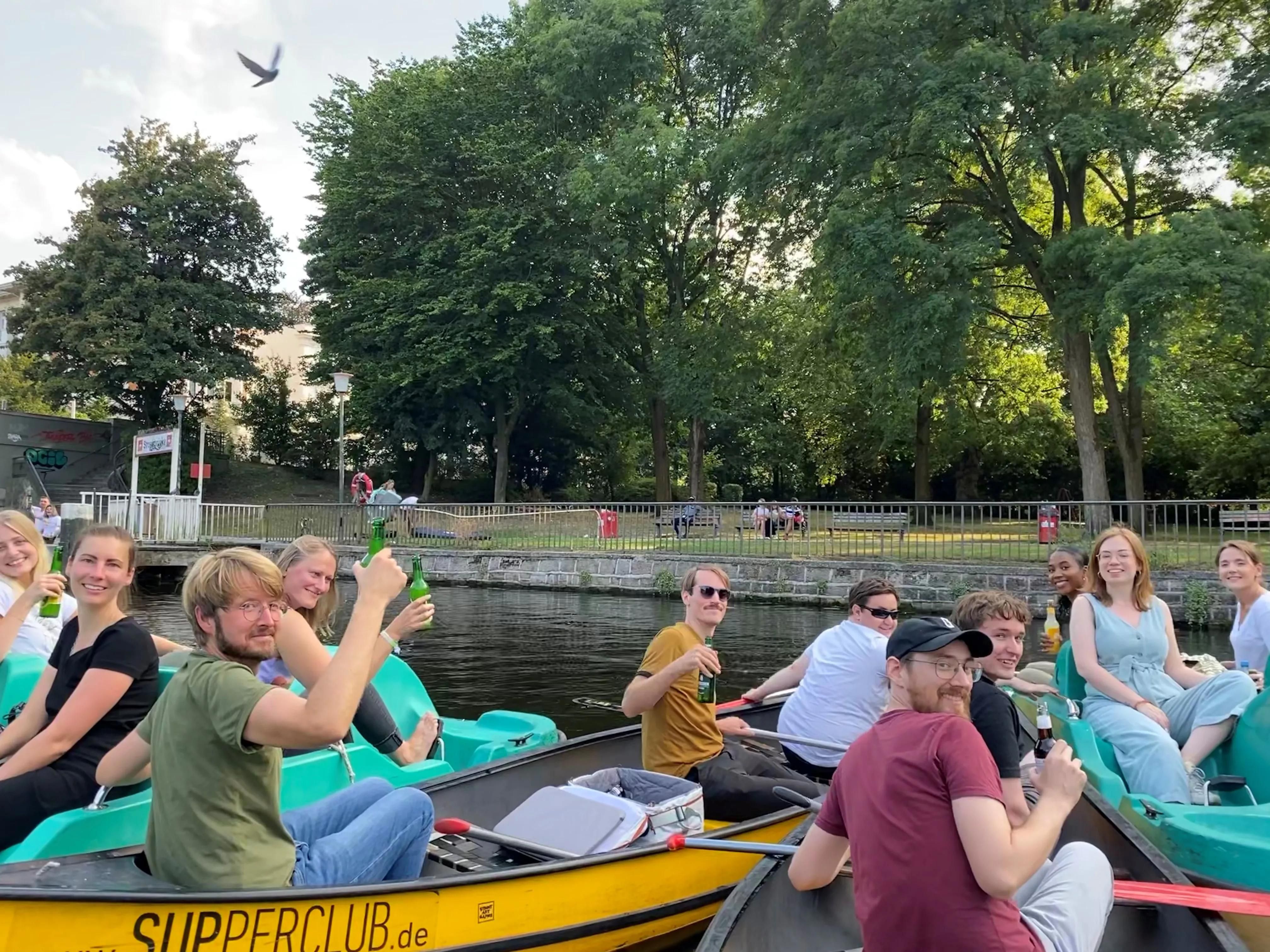 Das artaxo Team während des Sommerfests 2022 auf der Alster in Hamburg. Die Frauen und Männer sitzen verteilt auf Kanus und Tretbooten und prosten in die Kamera.