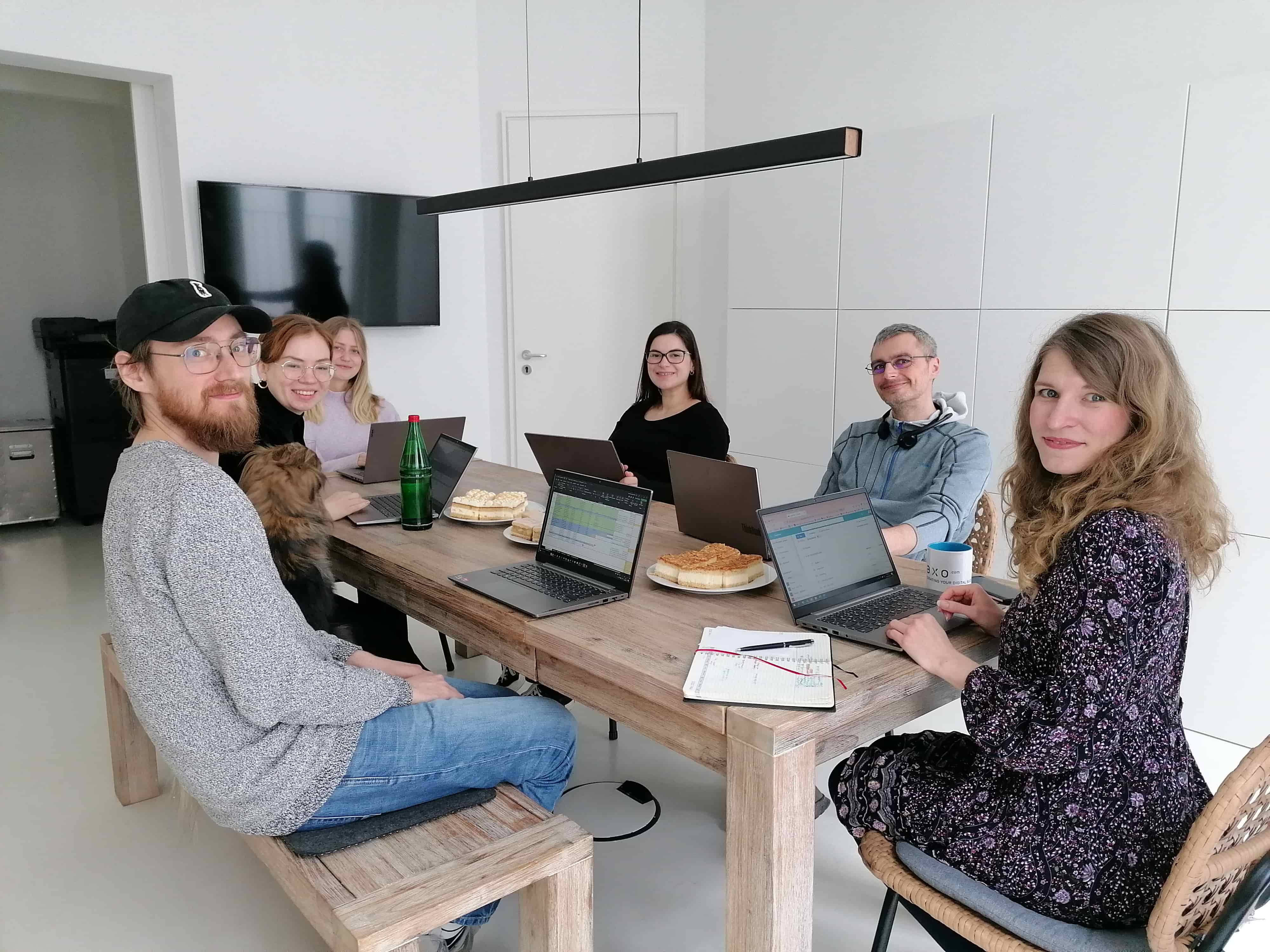 A Creation-team meeting in the office conference room. Team members and one dog smile at the camera.